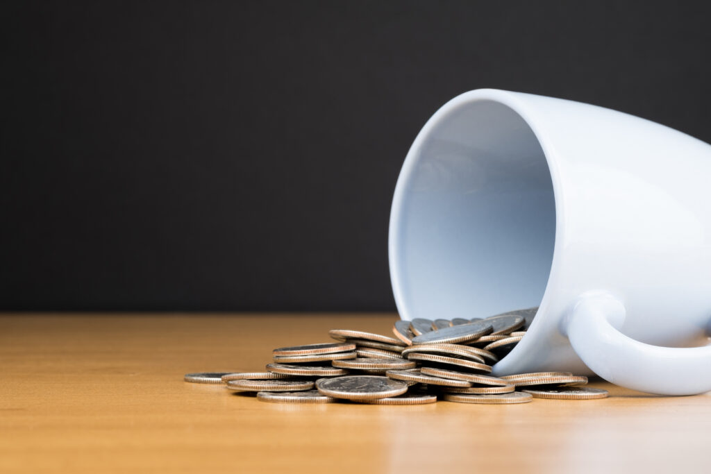 A cup on it's side with coins spilling out
